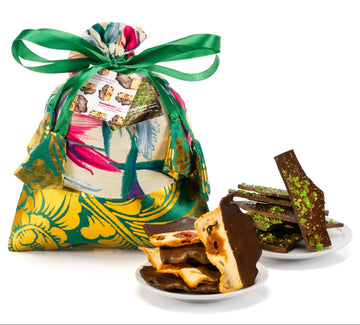 Decorative gift bag with a colorful design and a plate of assorted chocolates on a white background