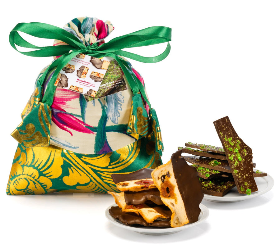 Decorative gift bag with a colorful design and a plate of assorted chocolates on a white background