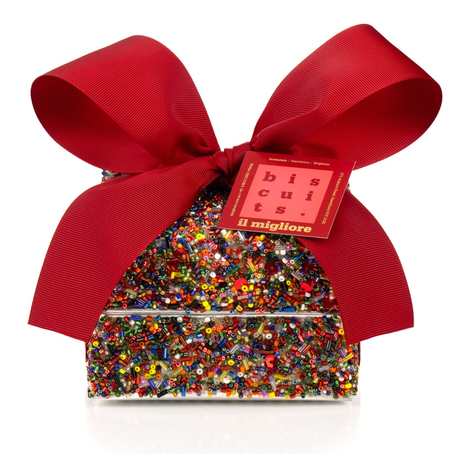 Decorative sequin box with delicious biscuits and a red ribbon on a white background