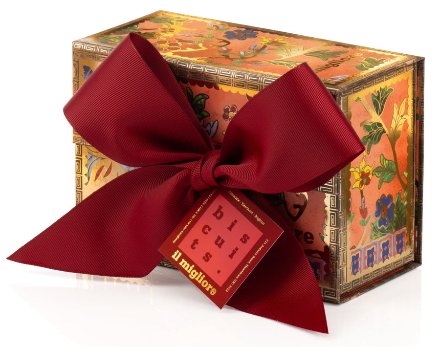 Decorative box with delicious biscuits and a red ribbon on a white background