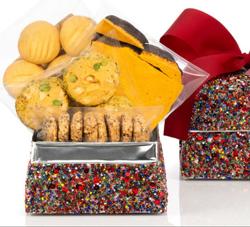 Decorative sequin box with delicious biscuits and a red ribbon on a white background