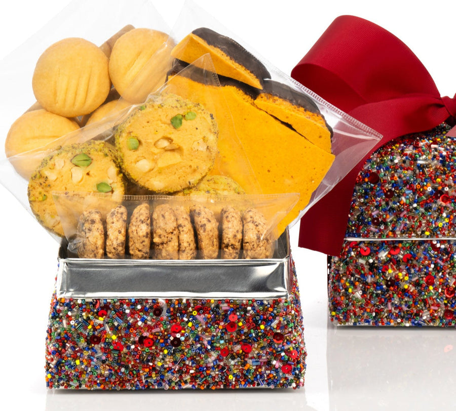 Decorative sequin box with delicious biscuits and a red ribbon on a white background