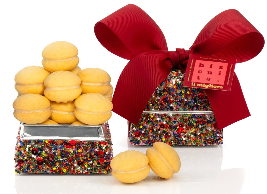 Decorative box with delicious biscuits and a red ribbon on a white background