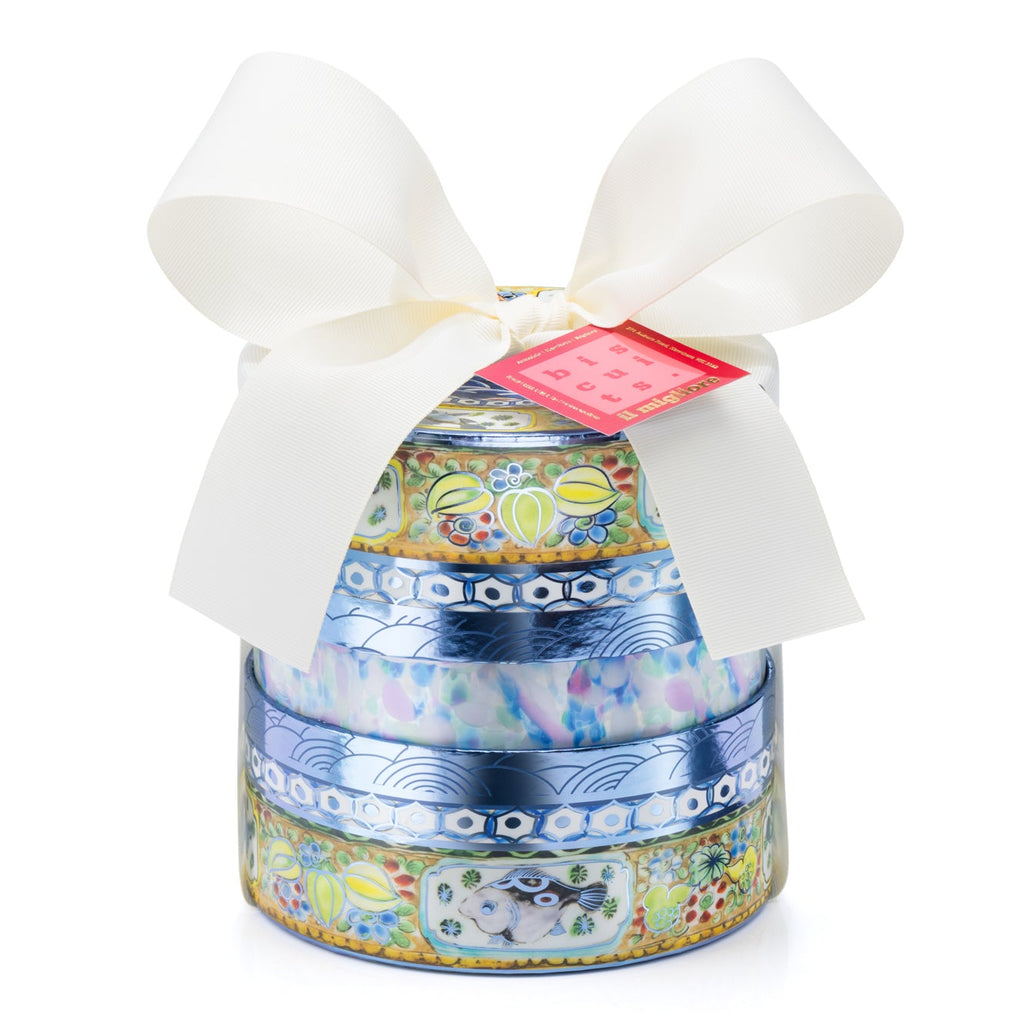 A round, tiered gift box with a white satin bow and a small red tag, featuring a blue and gold patterned design, isolated on a white background.